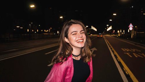 Portrait of smiling young woman on road at night
