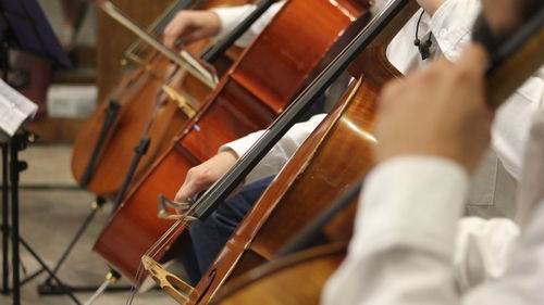 Midsection of men playing cellos in ceremony