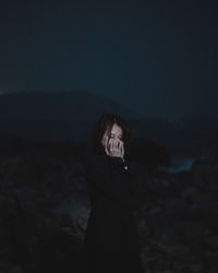 Woman standing at beach against sky at night