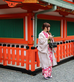 Full length of woman standing against building