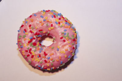 A pink donut with coloured sprinkles