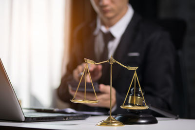 Midsection of man holding mobile phone on table