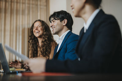 Happy young businessman sharing ideas with female colleagues in office