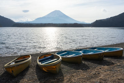 Boats moored on lake against mountains