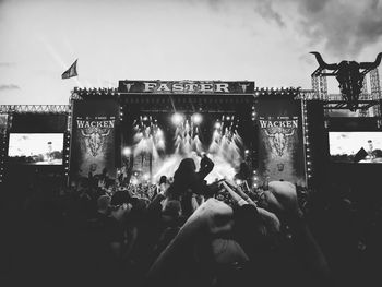 Crowd at music concert against sky at night