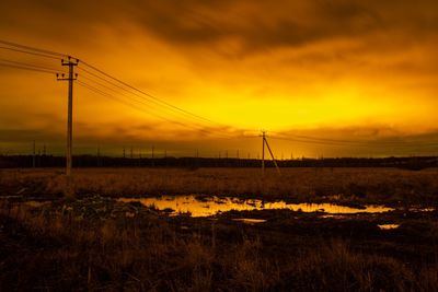 Electricity pylon on field against sky during sunset