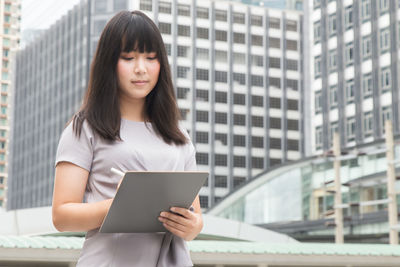 Young businesswoman standing against buildings in city