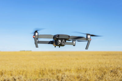 Quadcopter drone hovering over a wheat field