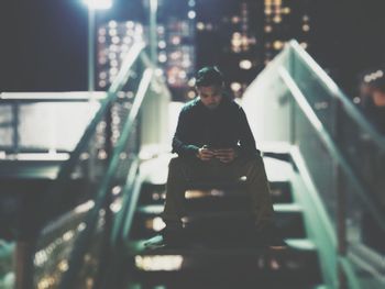 Full length of young man using mobile phone while sitting on steps