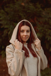 Portrait of beautiful young woman wearing hood standing outdoors