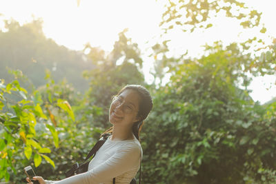 Portrait of a smiling young woman against plants