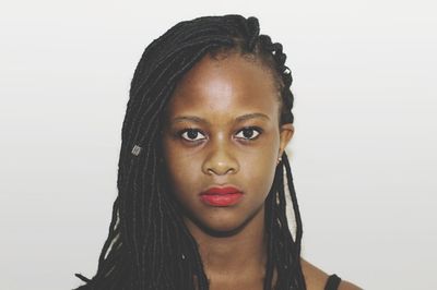 Close-up portrait of young woman with dreadlocks against white background