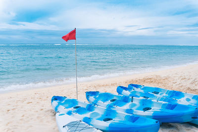 Deck chairs on beach against blue sky