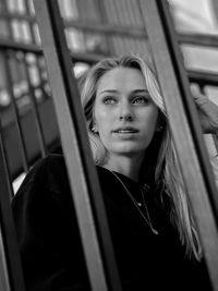 Portrait of young woman looking through window