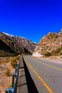 Road by mountains against clear blue sky