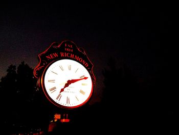 Low angle view of clock tower against dark sky