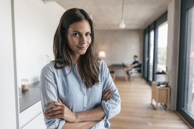 Portrait of smiling woman at home with man in background