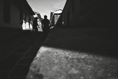 Silhouette people walking on road against sky