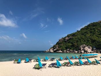 Deck chairs on beach against blue sky