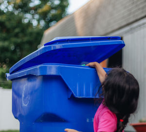 Cute girl standing by garbage bin outdoors