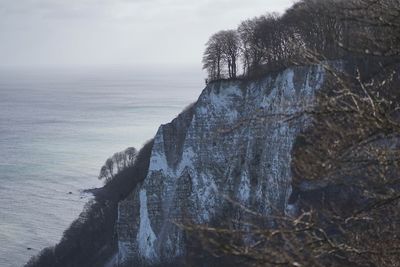 Scenic view of rocks by sea against sky