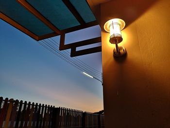 Low angle view of illuminated lamp on building against sky