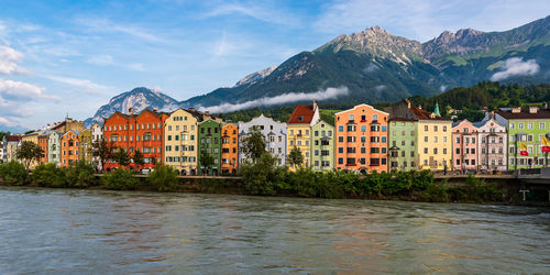 Houses by buildings and mountains against sky