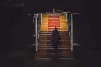 Silhouette man moving up steps at night