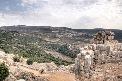 Scenic view of ruins of mountain against cloudy sky