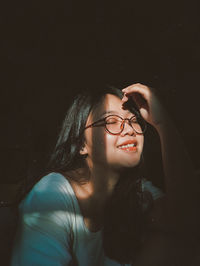 Smiling young woman eyes closed sitting in darkroom