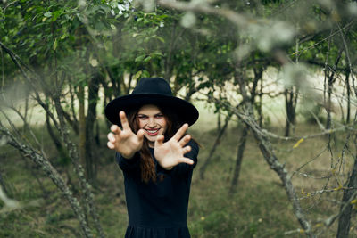 Portrait of young woman standing against trees