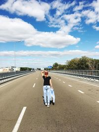 Rear view of woman standing on road against sky