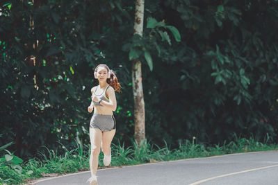 Woman standing on road amidst plants