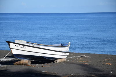 Boat moored on sea shore against sky