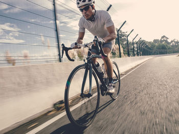 Full length of man riding bicycle on road by railing