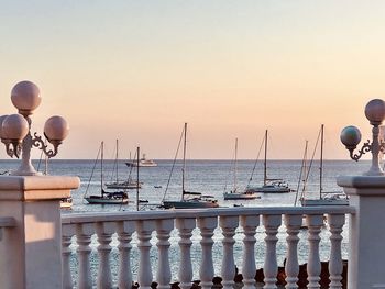 Scenic view of anchoring sailing boats against clear sky during sunset