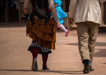 Low section of couple walking with road