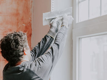 A caucasian young guy levels fresh putty with a spatula on a window opening