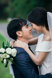 Close-up of newlywed couple embracing outdoors