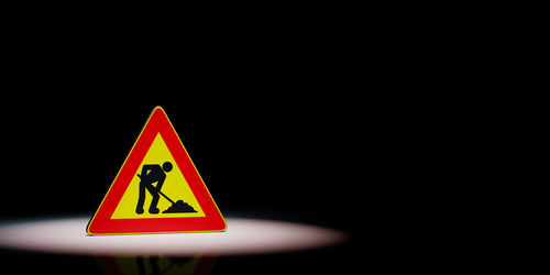 Close-up of road sign against black background