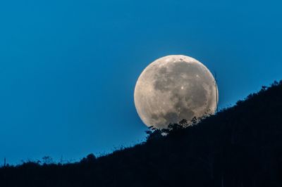 Low angle view of moon against clear blue sky