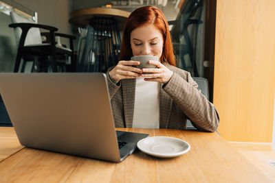 Young woman using mobile phone while sitting on table