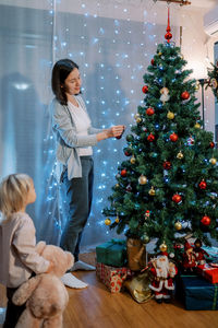 Rear view of woman holding christmas tree