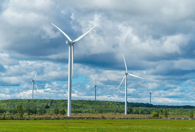 Windmills on field against sky