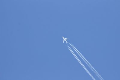 Low angle view of airplane flying against clear blue sky