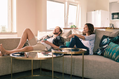 Couple enjoying coffee while resting on sofa in apartment