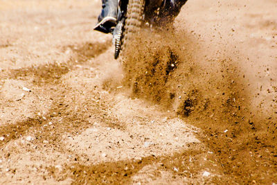 Close-up of motorcycle spraying dirt on land