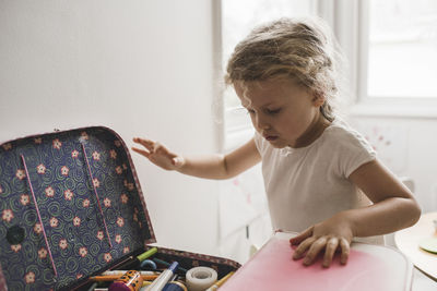 Girl searching for toys in suitcase at playroom