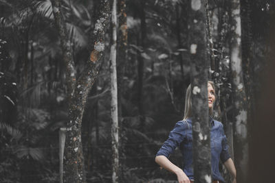 Young woman standing by tree in forest during winter