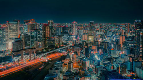 High angle view of illuminated city buildings against sky at night